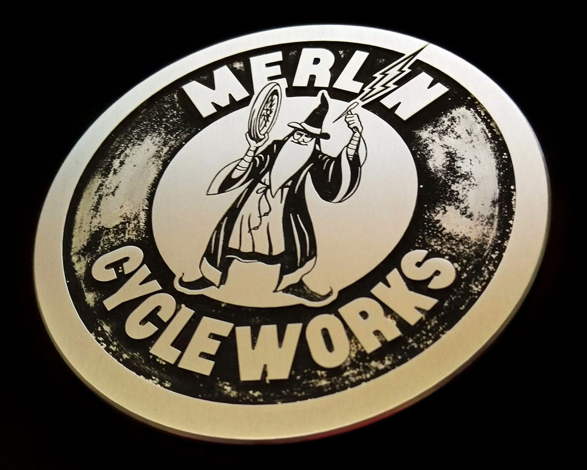 An aluminium motorcycle fuel tank emblem. Satin finish with a heavy patina in the recessed areas.